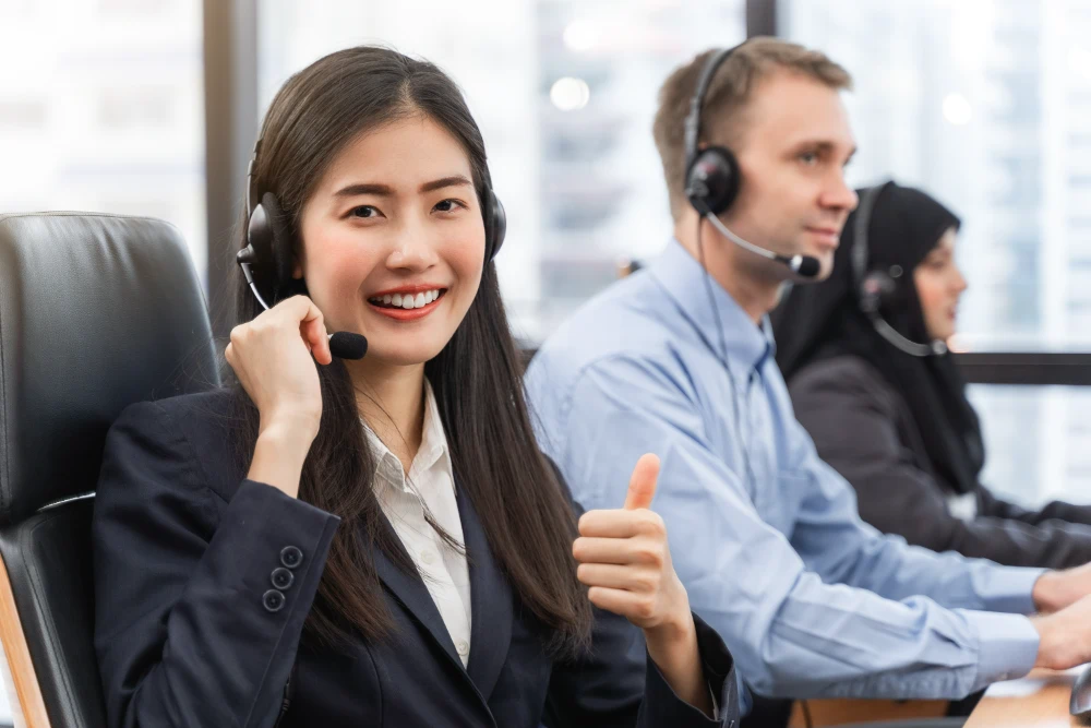 happy-smiling-operator-asian-woman-is-customer-service-agent-with-headsets-working-computer-call-center-talking-with-customer-assisting-resolve-problem-with-pose-thumbs-up